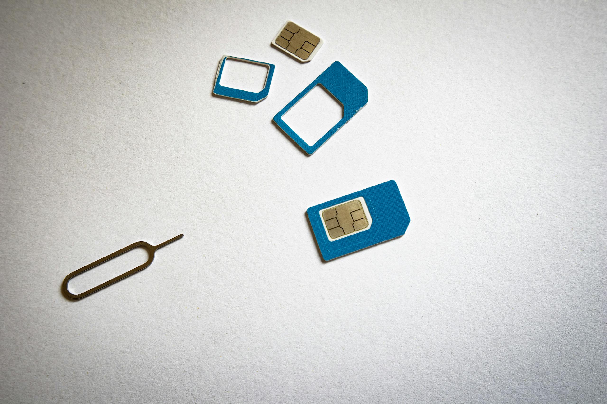 Close-up of SIM cards and ejector tool on white background, emphasizing telecommunication technology.